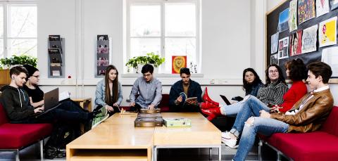 Tampereen lyseon lukion opiskelijoita istuskelee koulun aulassa.