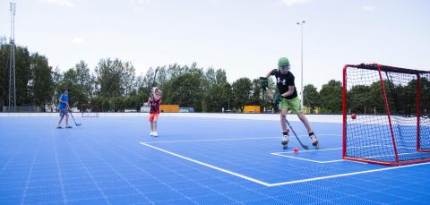 Blue floorball box outdoors and three children playing.