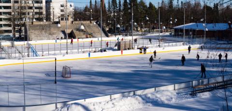  The ice rink is photographed from above. On the ice, players with sticks in their hands.