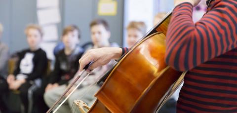 Lapset kuuntelevat, kun sellisti soittaa luokassa.