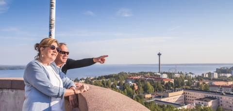 A couple gazing into the distance in the Pyynikki observation tower on a summer day