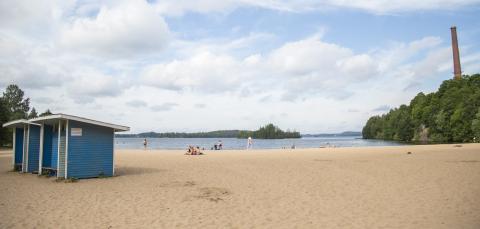 Sandy beach, changing rooms and swimmers on the beach.