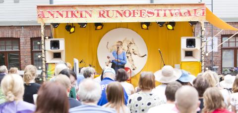 A woman reciting poems in front of an audience.