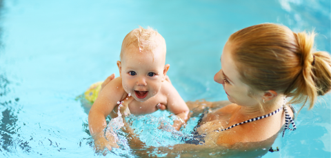 Baby in the swimming pool with his mom.