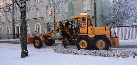 The snowplow is ploughing on the street.