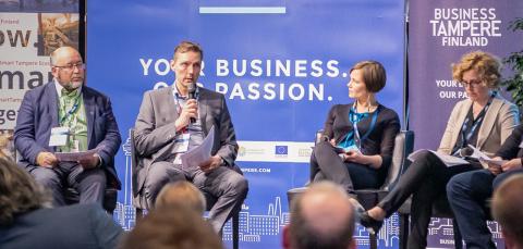 Seven people in panel discussion with one of them speaking to a microphone