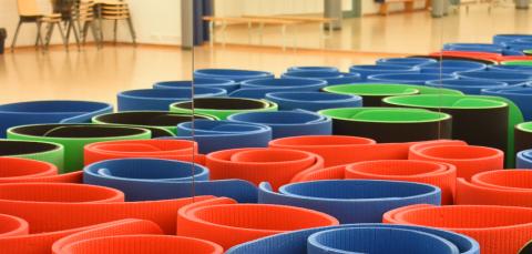 Jumppamattoja pystyssä rullalla liikuntasalin lattialla.