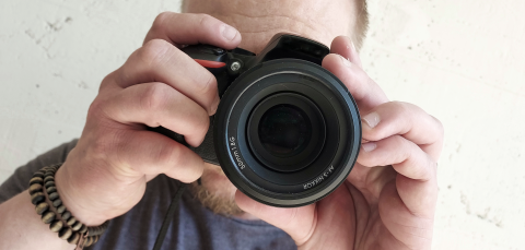 Henkilö pitelee kameraa käsissään.