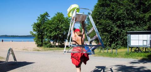 Uimavalvoja kantaa uimavalvojan tuolia aurinkoisella Pyynikin uimarannalla.