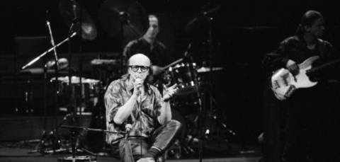Juice sitting on a chair singing on the stage of Tampere hall.