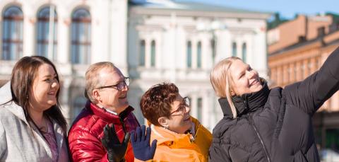Neljä henkilöä ottaa yhteisselfiekuvan Raatihuoneen edustalla.