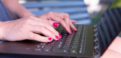 A person's hands typing on a computer.