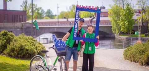 Turisti-infon oppaat hymyilevät kesäisen Tammerkosken rannalla.
