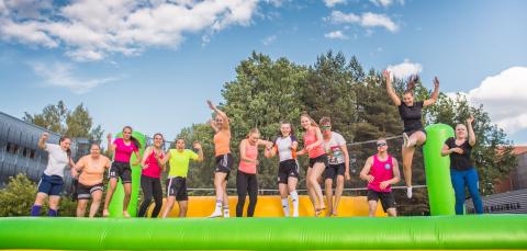 Young people jump in the air on a volleyball court.