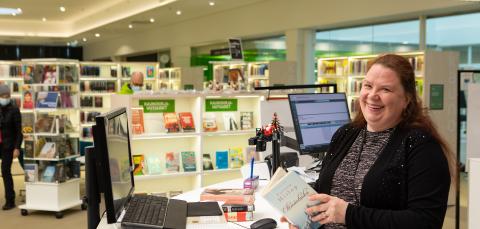 Ystävällisesti hymyilevä kirjaston työntekijä Lielahden kirjastossa.