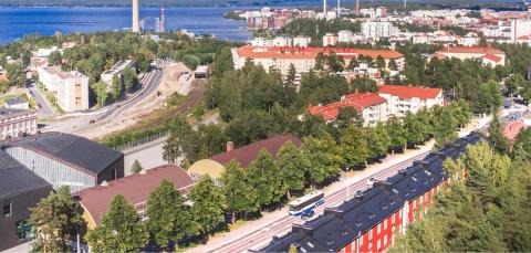 Ilmakuva Pyynikiltä kohti Särkänniemeä. Puustoa, rakennuksia ja teitä kesäisenä päivänä. Taustalla Näsijärvi.