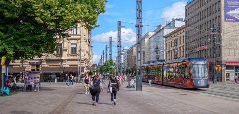 Ihmisiä kävelemässä Hämeenkadulla kesällä. Raitiovaunu ajaa kiskoilla.