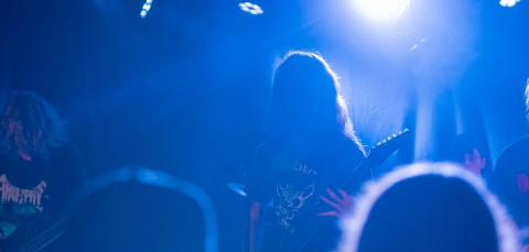 sininen kuva keikkatilanteesta, jossa yleisö ja bändi. 