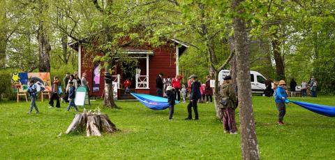 People in a green park with colourful works of art. Some hanging hammocks.
