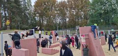 Ulkoilijoita parkouralueen välineillä.