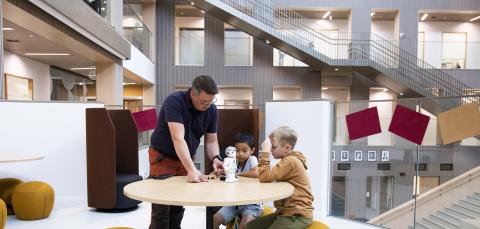 Opettaja ja kaksi oppilasta pöydän ääressä.