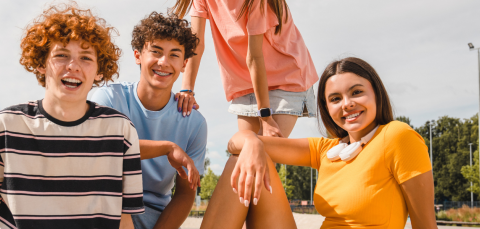 young people sitting in the park and looking into the camera smiling