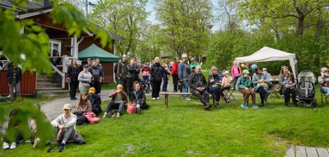 A large crowd of people are sitting outside waiting for the event to begin. 