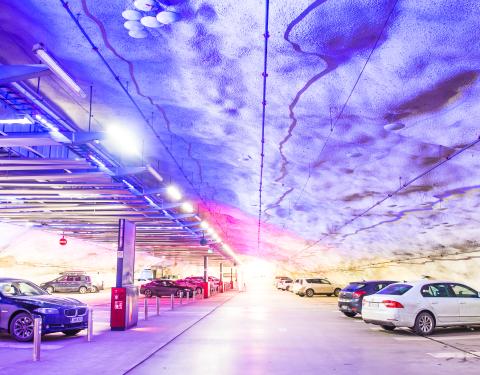 P-Hämppin pysäköintihalli maanalla sinisessä valaistuksessa, keskellä ajoväylä ja molemmin puolin autoja