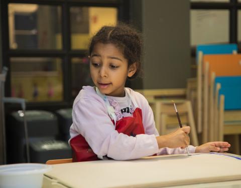 Child is painting with a water colour brush.