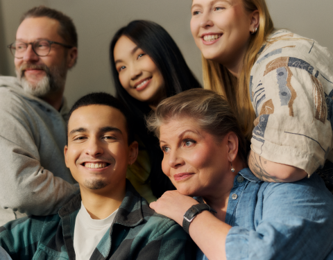 Five smiling people in a group photo.