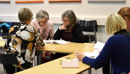 Viisi henkilöä tutkii kirjoja pöydän ääressä.