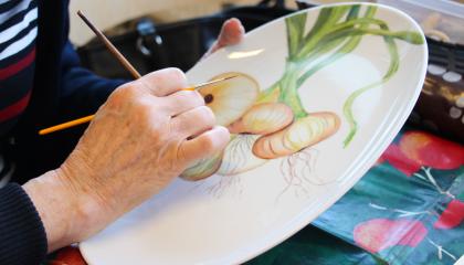 Posliinimaalaustyö, jota henkilö viimeistelee pensselillä.