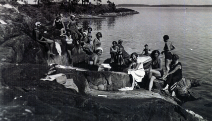 Joukko ihmisiä kallioisella rannalla.