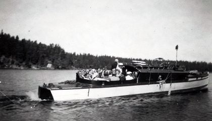 Vanha alus järvellä. Kyydissä on matkustajia.