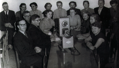 Joukko ihmisiä istuu epidiaskoopin ääressä.