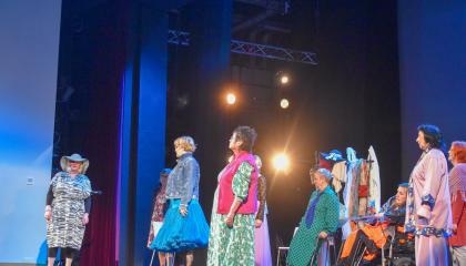 Henkilöt seisovat esiintymässä lavalla.