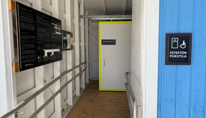 Pyynikin esteettömän uimarannan käytävä pukutilaan, jossa ohjeet ja apuvälineen säilytyspaikka.