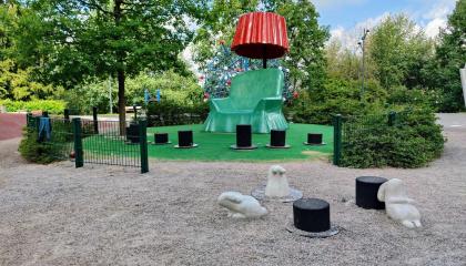 Vihreä jättinojatuoli ja punainen lukulamppu, taikurinhattuja ja kaneja lukunurkkauksessa.