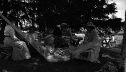 A child sits in a hammock and the ladies behind at a table in Haihara.