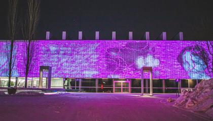 Yliopiston keskustakampuksen päärakennuksen ulkoseinään projisoitu pinkki valotaideteos.