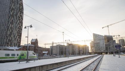 Aamuaurinkoinen kuva rautatieasemasta radoilta kuvattuna.