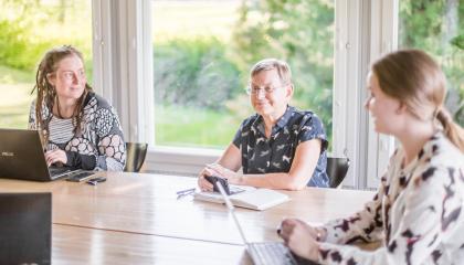 Kolme naista työpöydän äärellä suunnittelemassa.