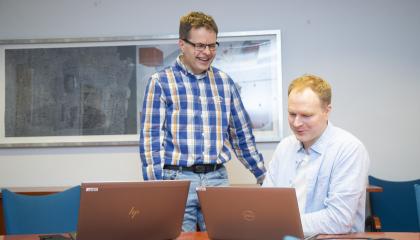 Paikkatietoasiantuntijat katsovat kannettavan tietokoneen näyttöä kokoushuoneen pöydän ääressä.