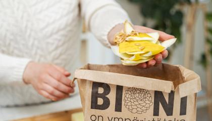 Asukas laittaa hedelmäjätettä paperiseen biojätepussiin.