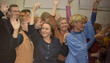 Henkilöt seisovat kädet ylhäällä ja tanssivat.