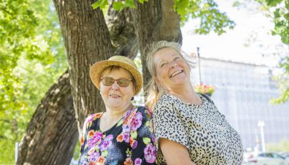 Kaksi iloista naista selät vastakkais kesällä puistossa.