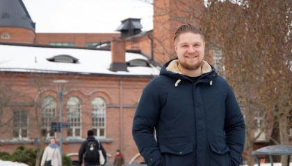 Henkilö seisoo ulkona talvisessa säässä ja katsoo kameraan.