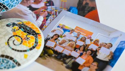 Kaksi valokuvaa pöydällä ihmisistä. Pöydällä on myös värikäs keramiikkatyö.