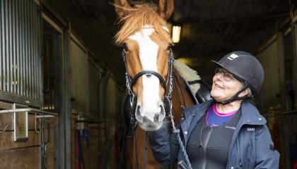 Sari Maunula on talillla ja pitelee kiinni Stara hevosen riimusta.
