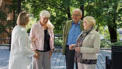 Neljä eläkeiän saavuttanutta tamperelaista keskustelee keskenään iloisesti hymyillen.